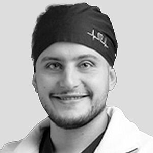 Alex Fneiche Portrait image of Alex Fneiche in black and white: you see his head covered with a surgical cap as well as his smiling face.